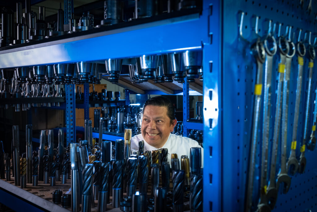 A man smiles behind a shelf of tool bits.