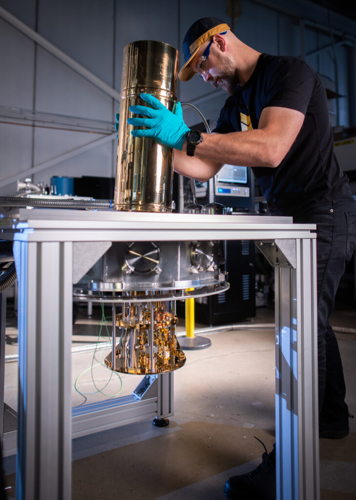 A man places a gold cylinder into a hole in a silver table.